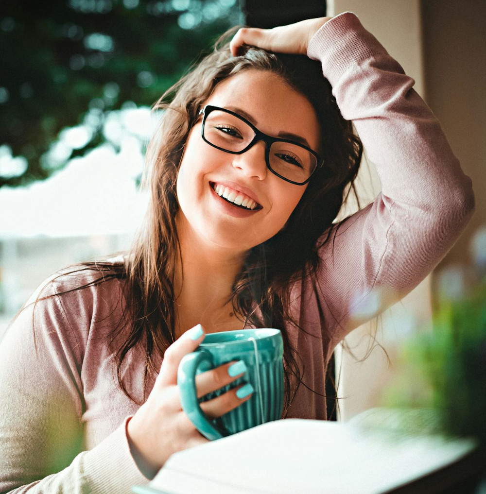 young woman with glasses drinks tea